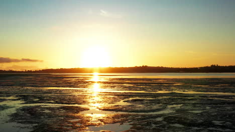 Rear-aerial-sunset-above-shallows-and-low-coastline-tide-near-Auckland