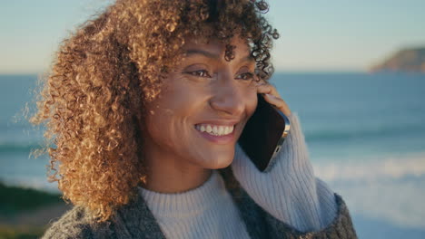 curly woman laughing cellphone at ocean closeup.   girl calling