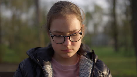 Portrait-of-serious-girl-sitting-in-park.-Teenager-girl-feeling-sad-outdoors.