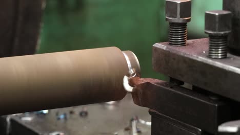 el torno continúa procesando el bloque de metal cilíndrico y corta las fichas