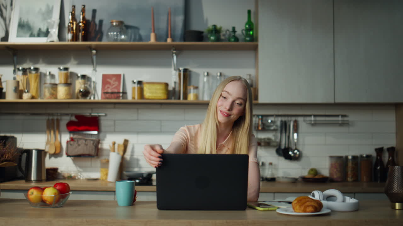 Woman finish video call closing laptop on kitchen. Girl manager working remotely