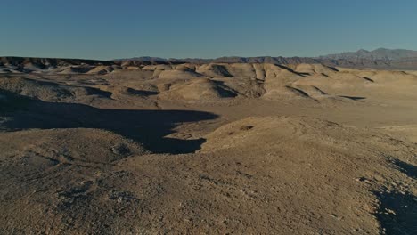 slow, aerial view moving over dry, barren mudstone embankments in a desert