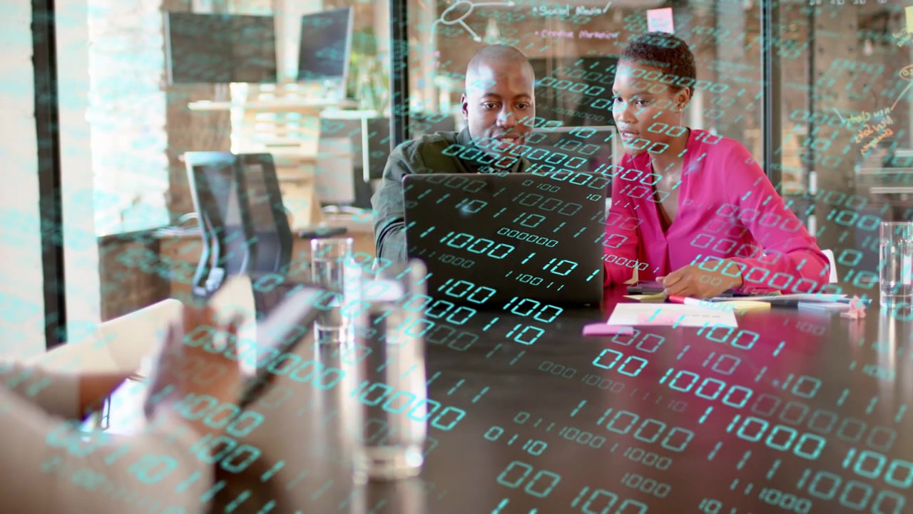 Two colleagues using laptop, foreground hand tapping tablet and starting data overlay for business