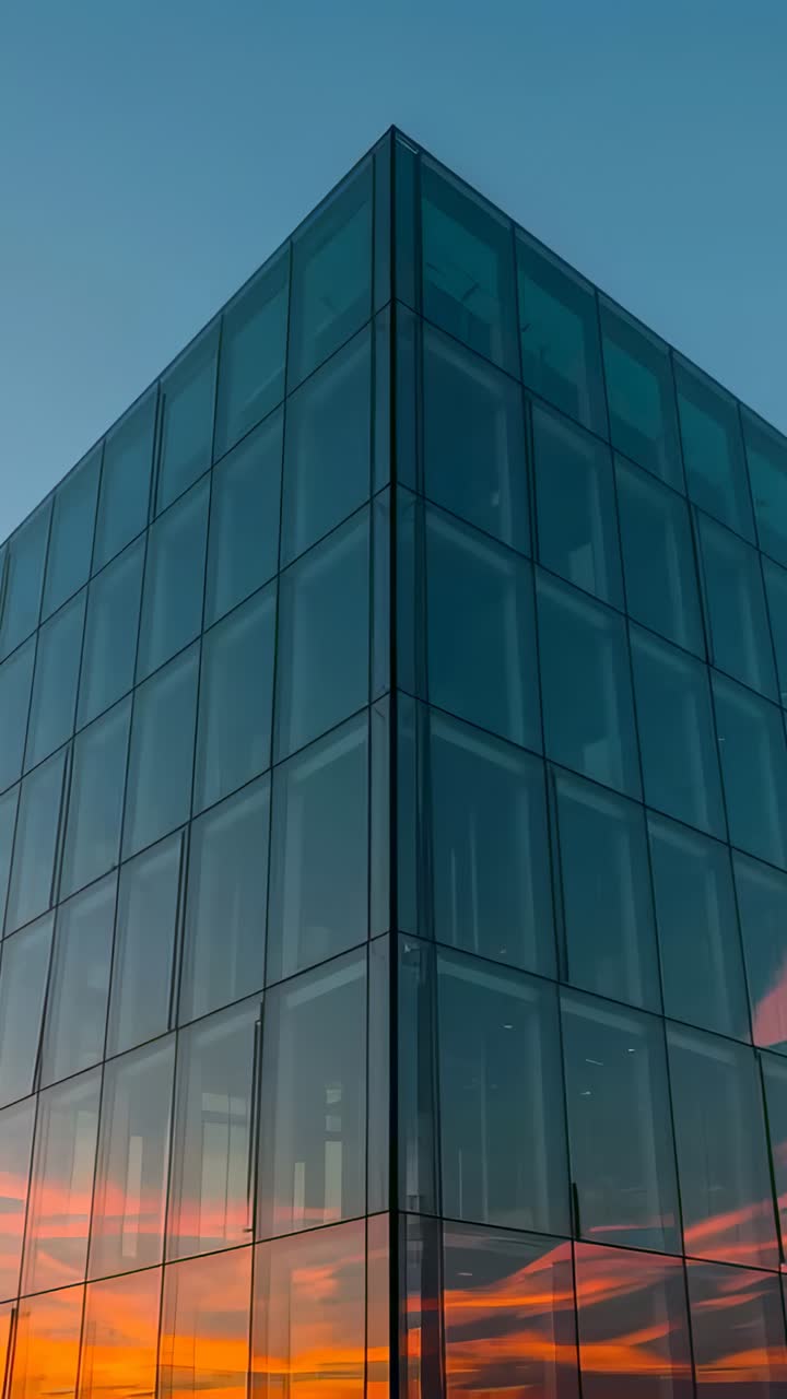 Video verticale: panoramica con camera che passa l'angolo di un ufficio al tramonto, rivelando riflessi di nuvole rosa