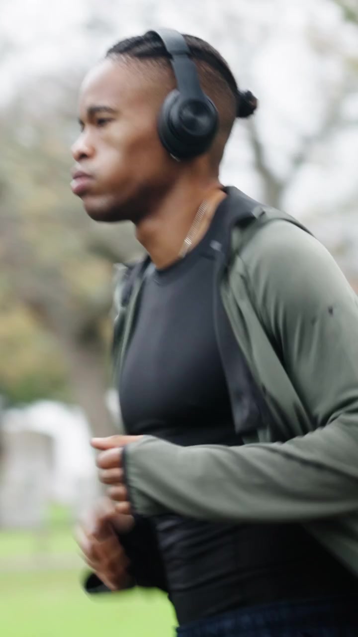 Giovane uomo che fa jogging al parco indossando le cuffie