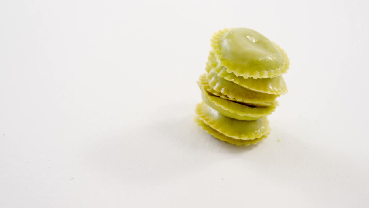 pila de pasta de ravioli casera verde en un fondo blanco