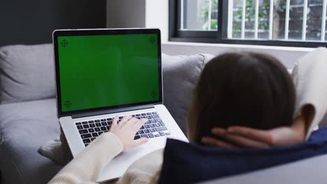 Vista-Por-Encima-Del-Hombro-De-Una-Mujer-Caucásica-En-Casa-Recostada-En-Un-Sofá-En-La-Sala-De-Estar-Usando-Una-Computadora-Portátil