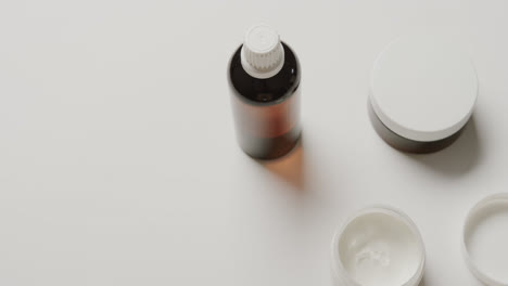 close up of cream tubs and glass bottle with copy space on white background with copy space