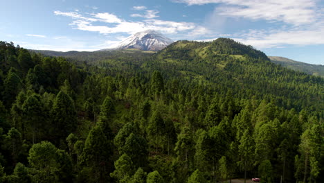 Rückwärts-Drohne,-Die-Die-Schneebedeckte-Spitze-Des-Vulkans-Popocatepetl-In-Mexiko-Stadt-Und-Die-üppigen-Wälder-Zeigt,-Die-Ihn-Umgeben