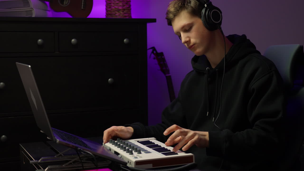 Male musician leans over keyboard creating new melody in home studio during calm focused session
