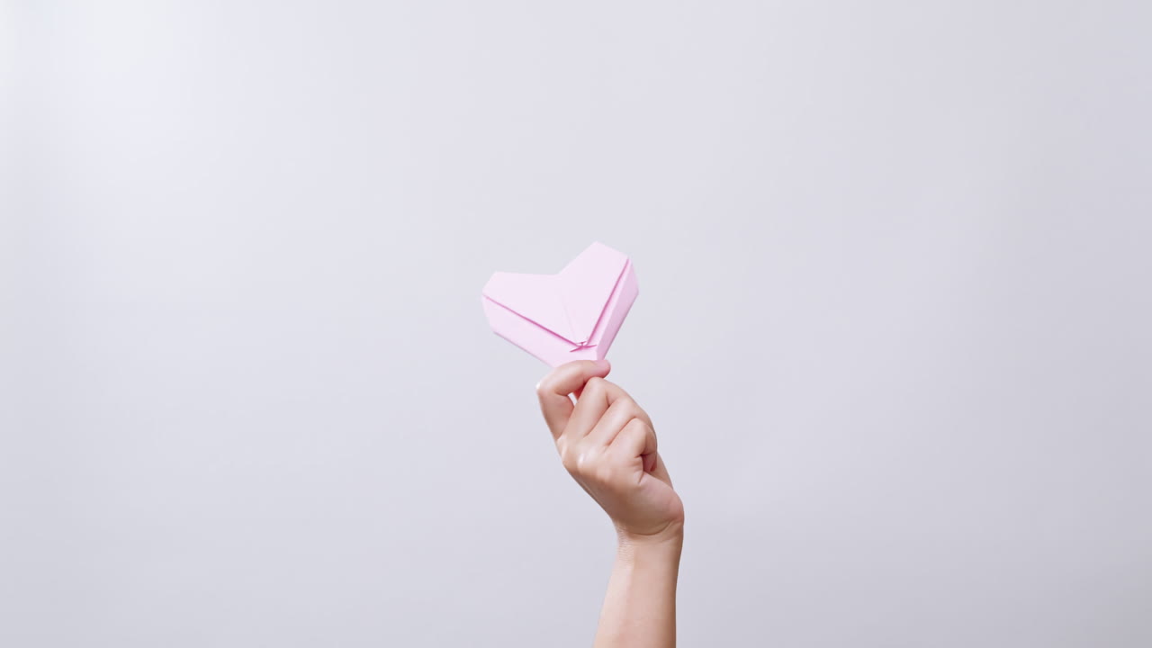 женщина держит бумажное сердце на белом студийном фоне с копировальным пространством