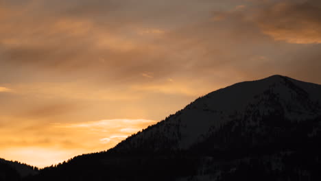 glowing orange sunset over snowy mountains in natonal park during winter golden hour with alpenglow 4k 30fps prores