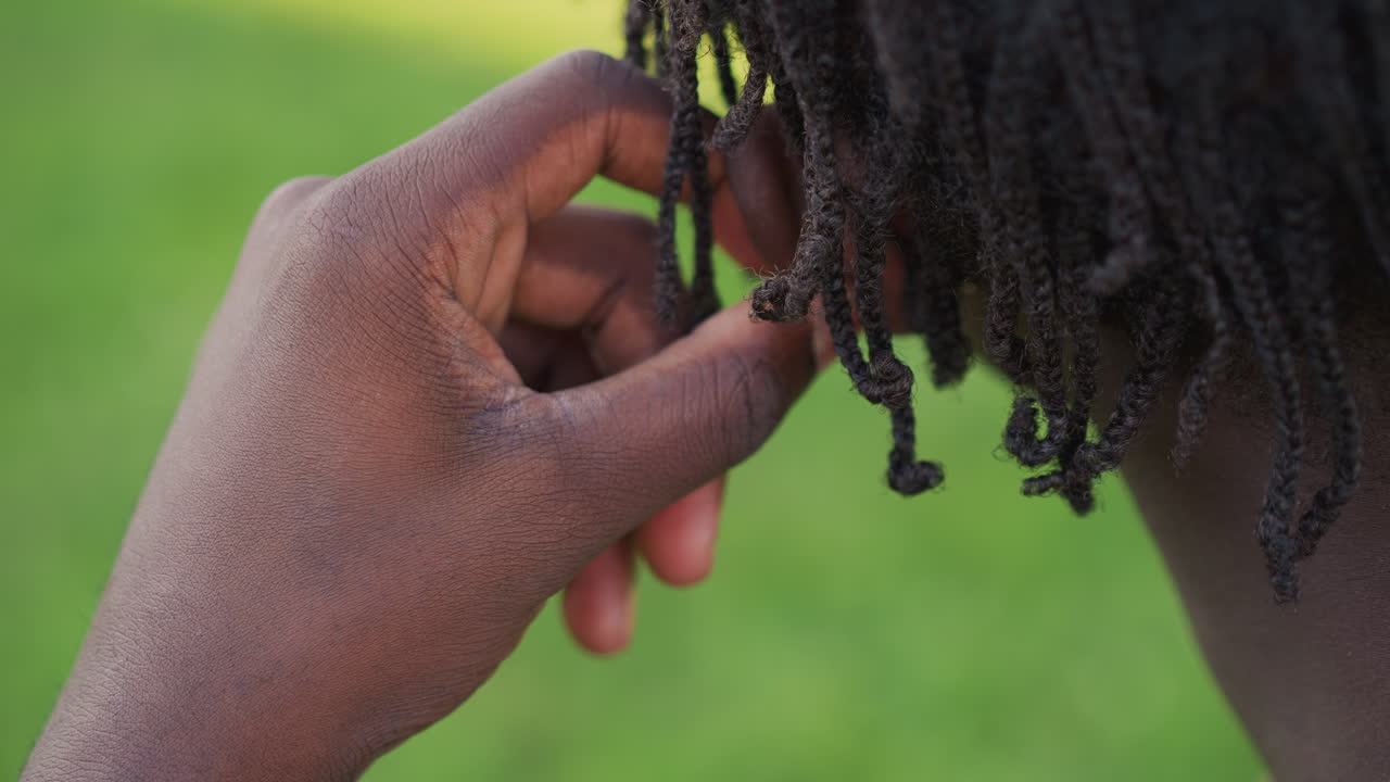 Black Soldier Grooming Dreadlocks With Careful Fingers In Backyard, CloseUp Of Textured Locs And Hands Showing Maintenance Routine And Mindful Selfcare Under Soft Daylight Personal Ritual