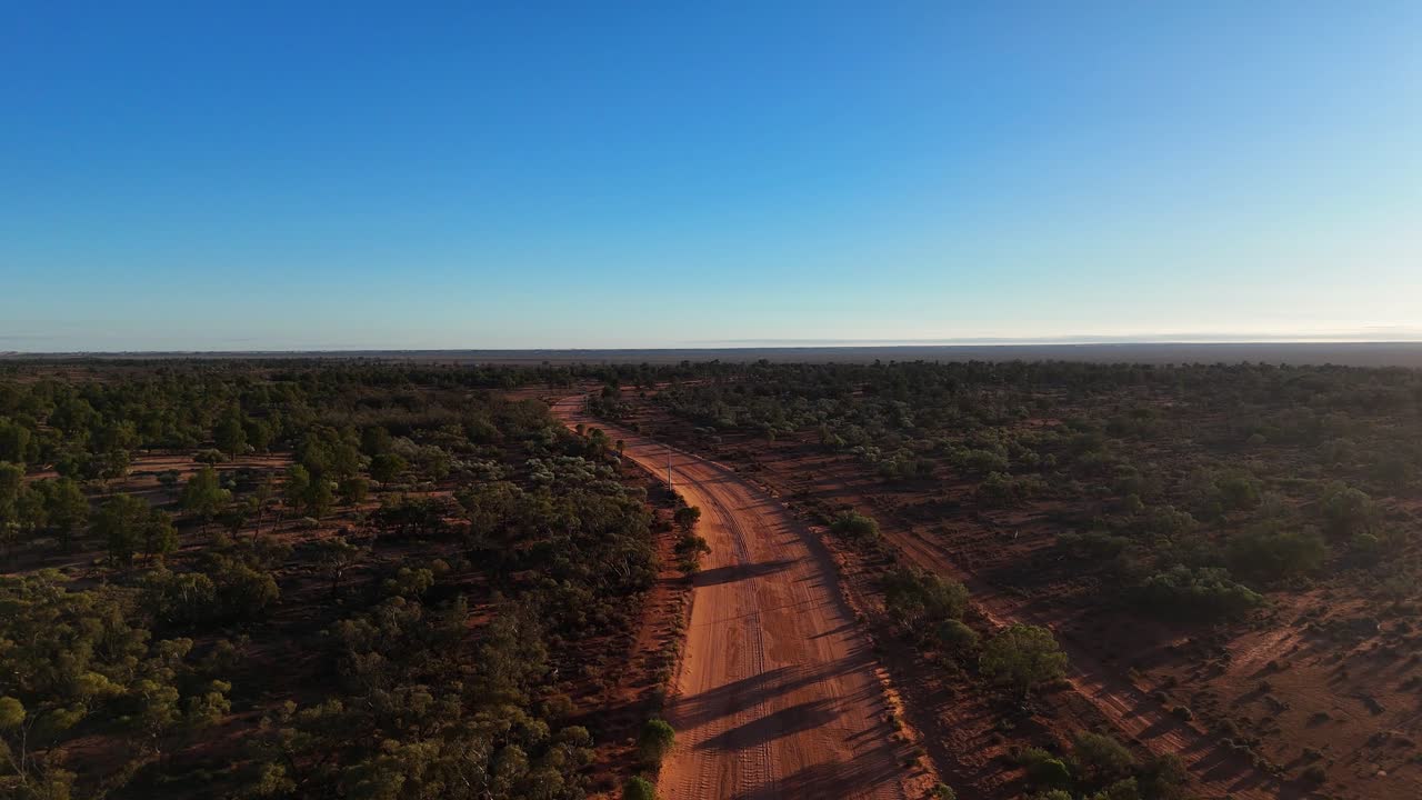 Vista aerea dell'entroterra remoto del Nuovo Galles del Sud con strada sterrata che attraversa un vasto paesaggio arido sotto un cielo limpido, natura selvaggia australiana