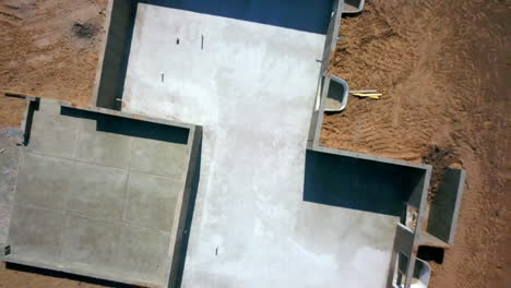 a drone shot backing away straight up from a foundation and basement walls that had just been poured