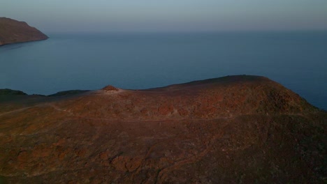 Sunset-casting-a-beautiful-orange-hue-on-hill-side,-with-Atlantic-Ocean-as-a-backdrop