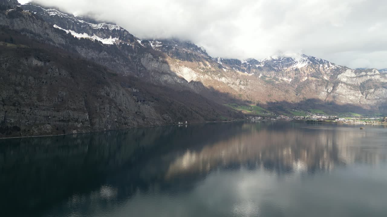 desde una perspectiva aérea, la belleza escarpada de los paisajes montañosos juxtapuestos con una pintoresca zona residencial, todo contra el impresionante telón de fondo de walensee unterterzen, suiza