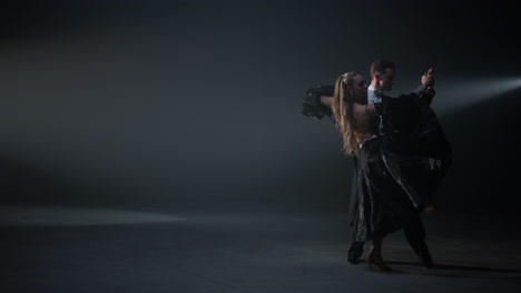 ballroom dance couple performing indoors. passionate dancers moving on stage.