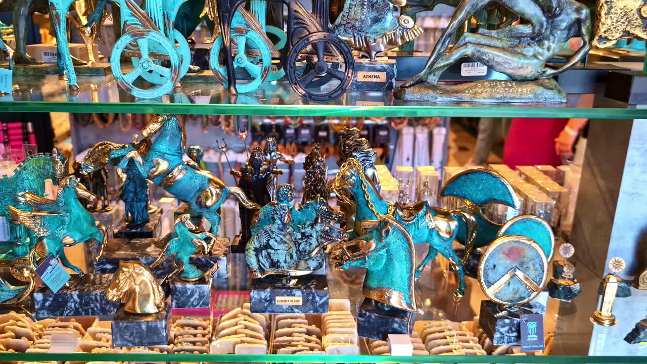 A vibrant shelf display featuring detailed turquoise and gold figurines, statues and decorative items in a gift or souvenir shop