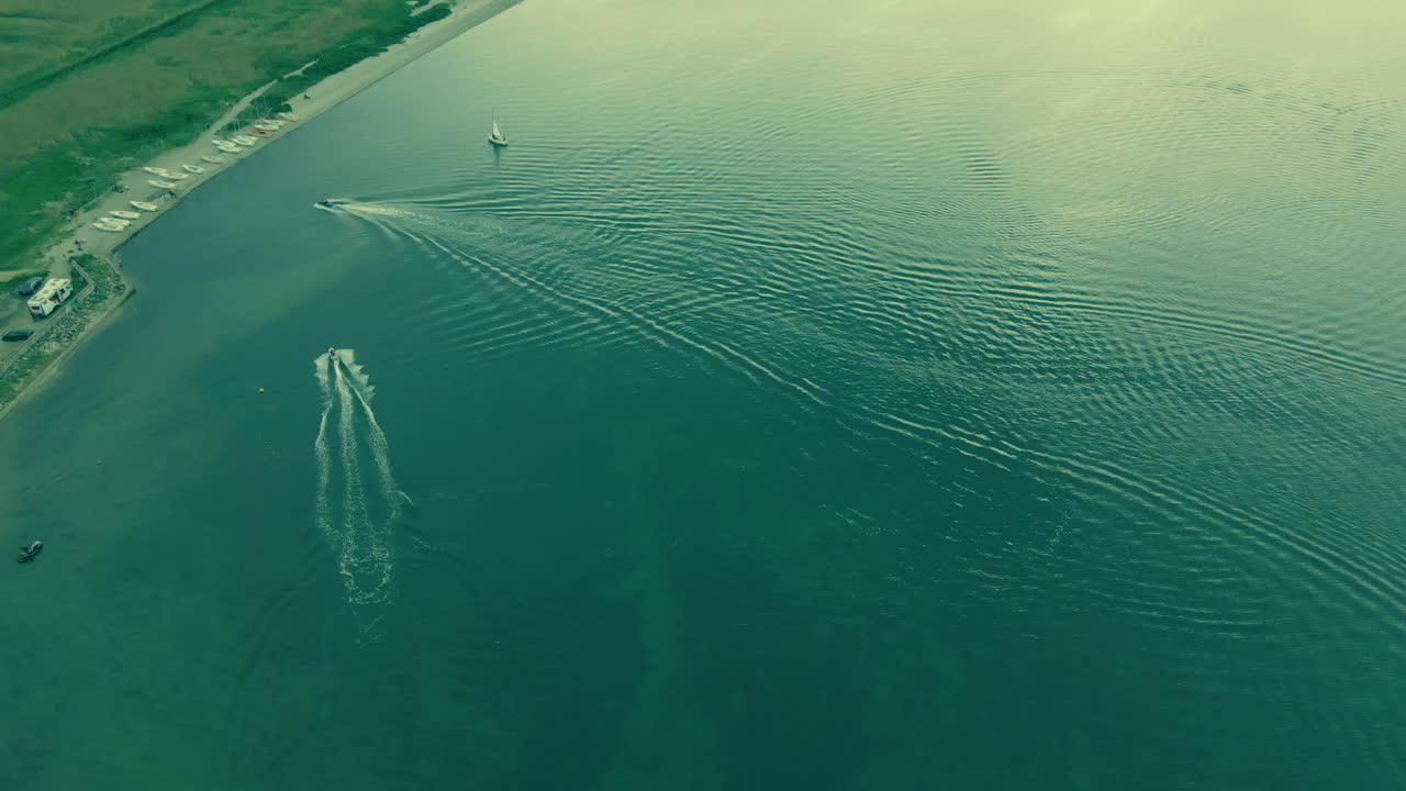 Aerial shot motorboat sails on green water sea, boat on the left top