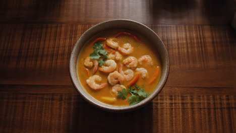 a bowl of shrimp curry on a wooden table