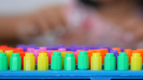 child playing with colorful plastic pegs on a game board