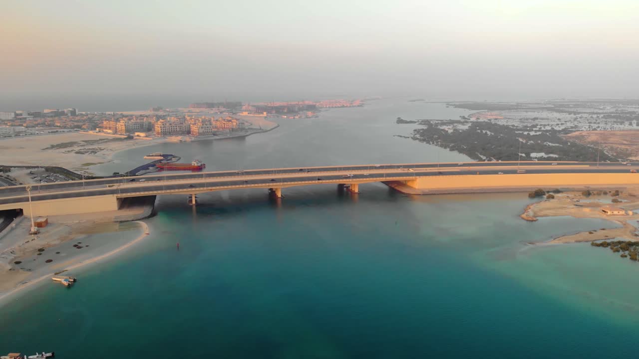 dron de gran altitud que sigue a los coches que conducen sobre el puente de aguas turquesas de abu dhabi