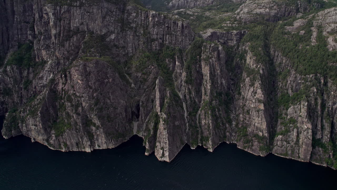 Wide aerial shot, pushing in on the cliffs beneath Preikestolen, by Lysefjord in Norway