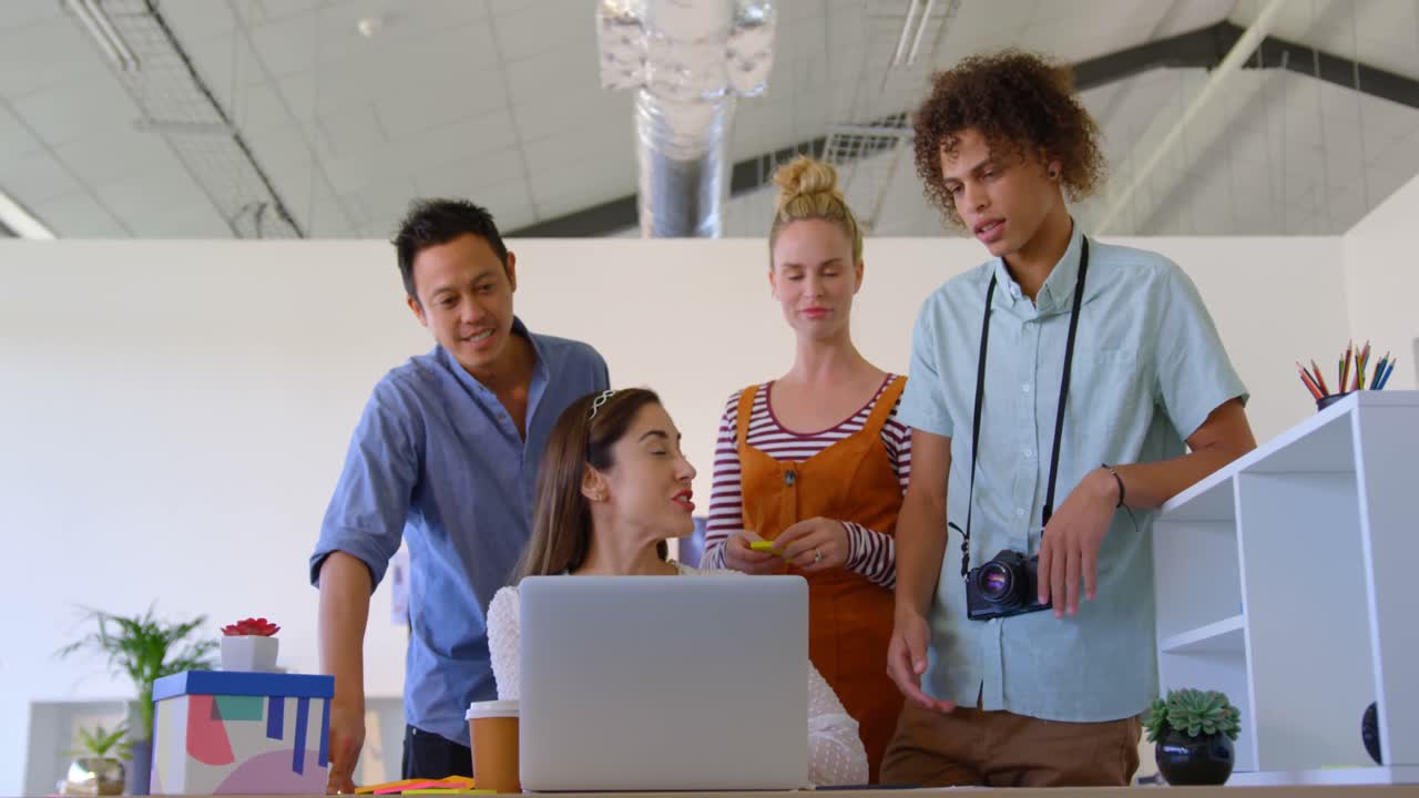 Caucasian businesswoman working on his laptop is interacting with others business people in a office