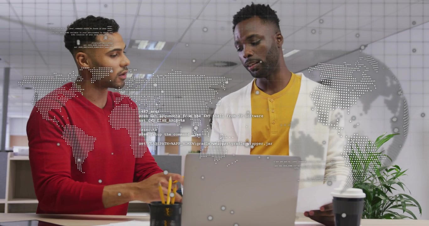 Two men reaching pencil, pointing laptop, reviewing paper, tapping device, map overlay aiding biz