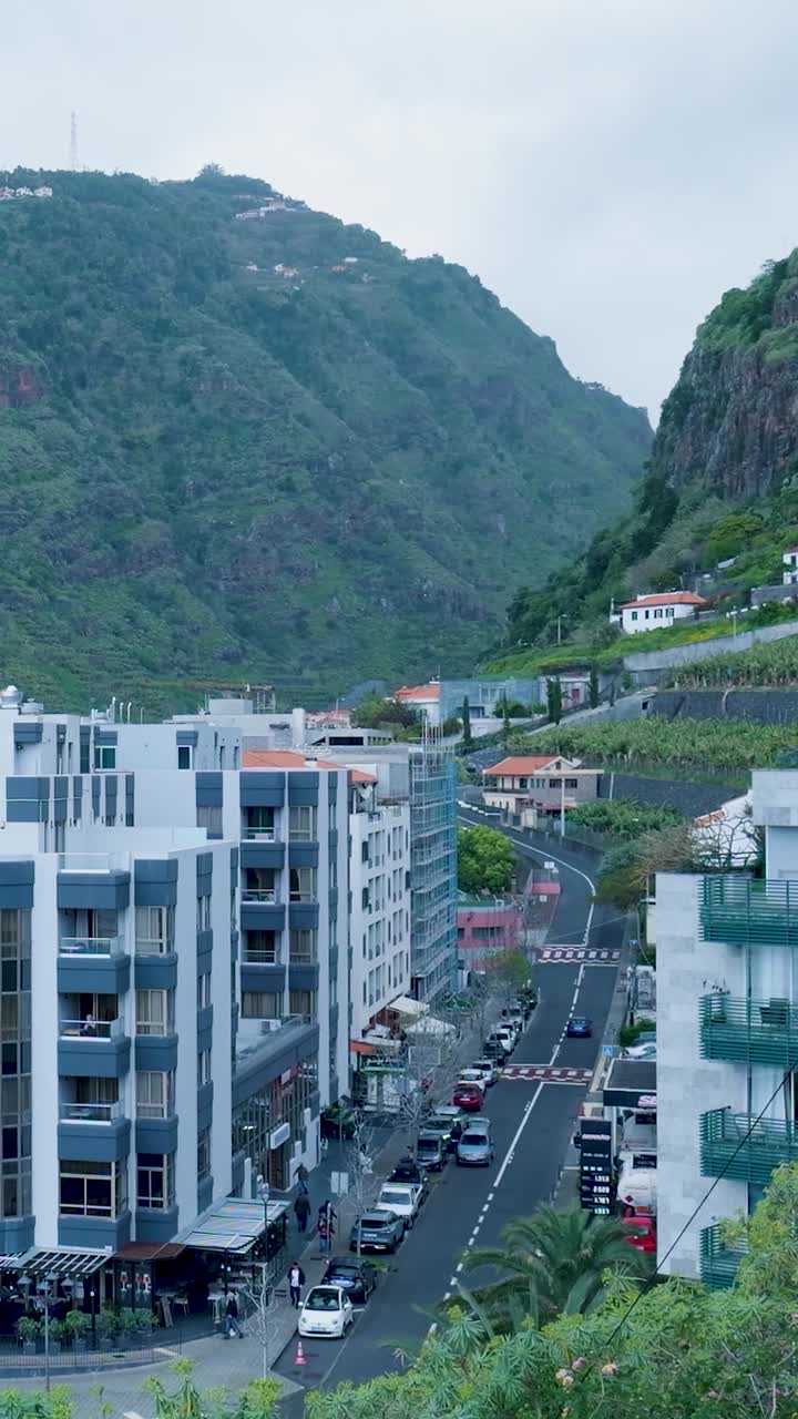Rua Urbana em um Vale de Montanha com Edifícios e Carros em Movimento