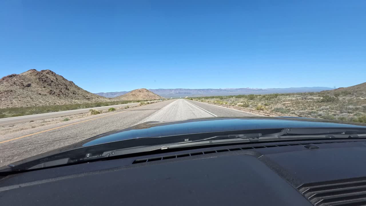 vista sobre el capó de un coche mientras conduce la autopista interestatal en california con montañas en el fondo