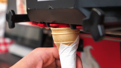hand picking an ice cream cone from a machine