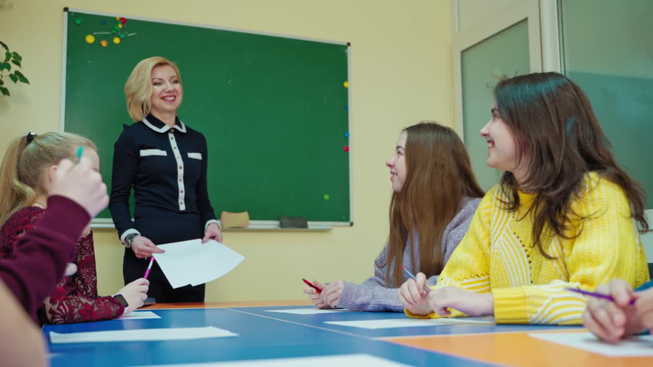 Experienced teacher with students. Teen schoolgirl talking to the teacher in the classroom. Educational process at school. Back to school.