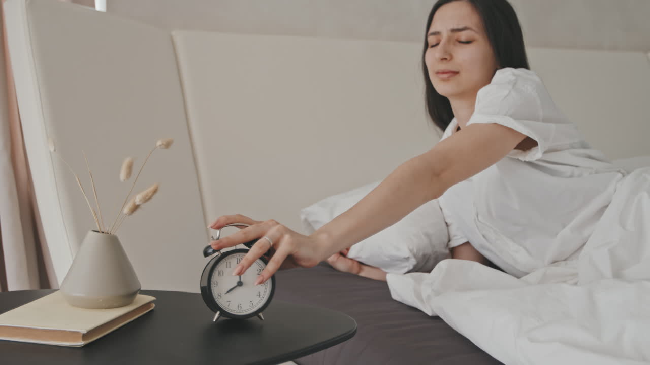 Sleepy Young Woman Turning Off Alarm Clock