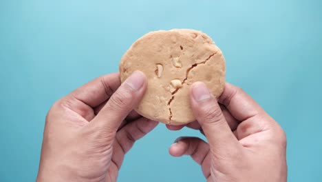 hand holding a broken peanut butter cookie