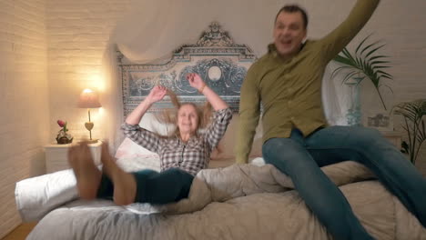 happy young couple jumping on the bed