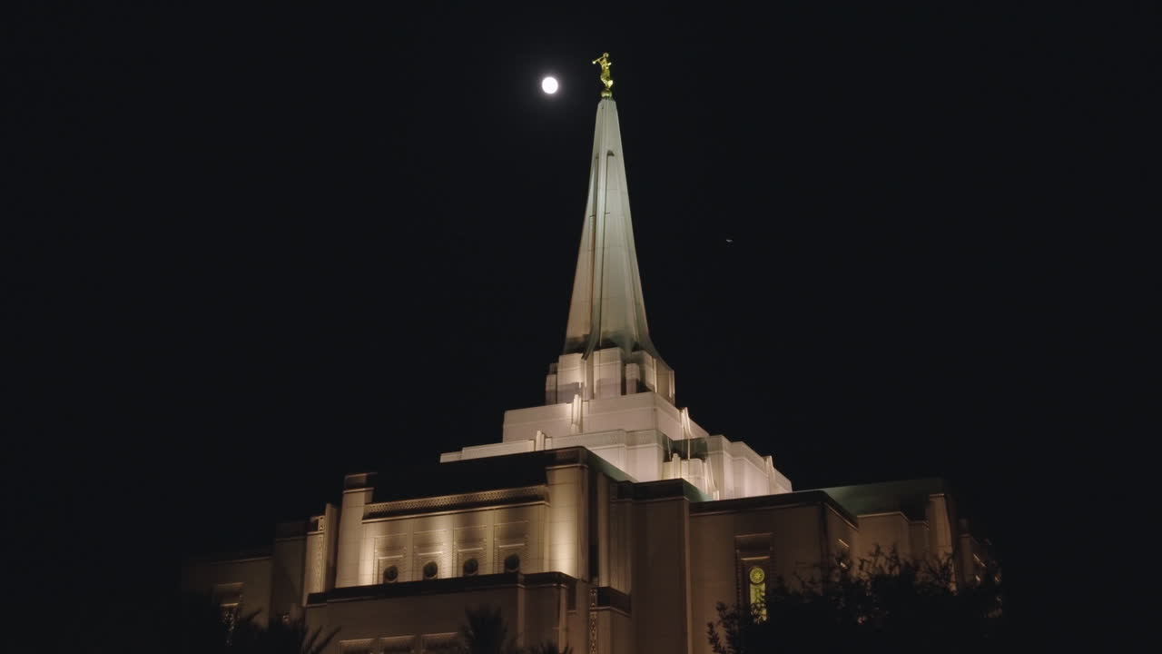 첨탑 주위를 날아다니는 새들과 함께 밤에 달빛에 비치는 lds 사원 백라이트 | 애리조나 주 길버트에 있는 모르몬 교회 건물