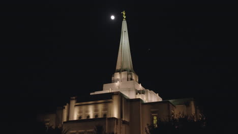 templo lds retroiluminado por la luna en la noche con pájaros volando alrededor de la aguja | edificio de la iglesia mormona en gilbert, arizona