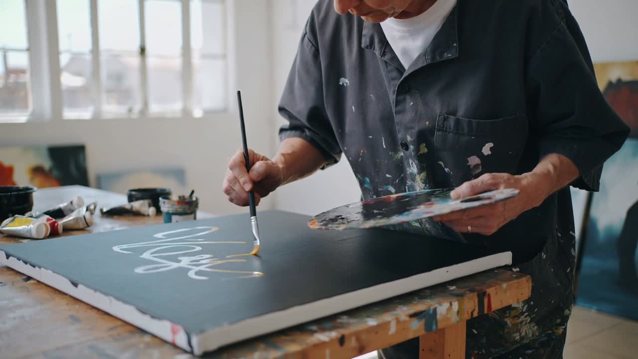 Immergendo il pennello nella vernice gialla, l'artista in studio applica pennellate sulla tela per creare linee e una tavolozza.