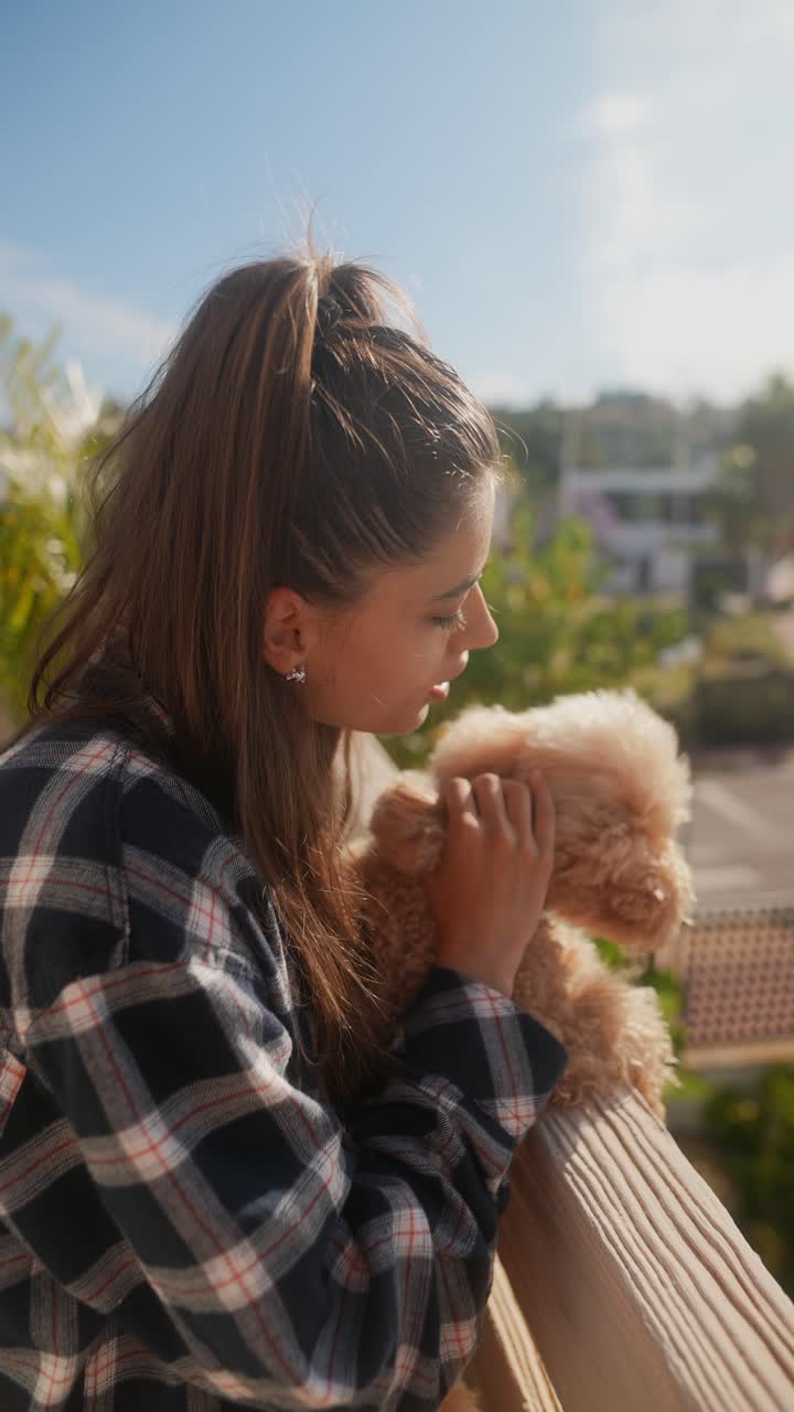 발코니에서 테디 베어를 안고 있는 젊은 여성