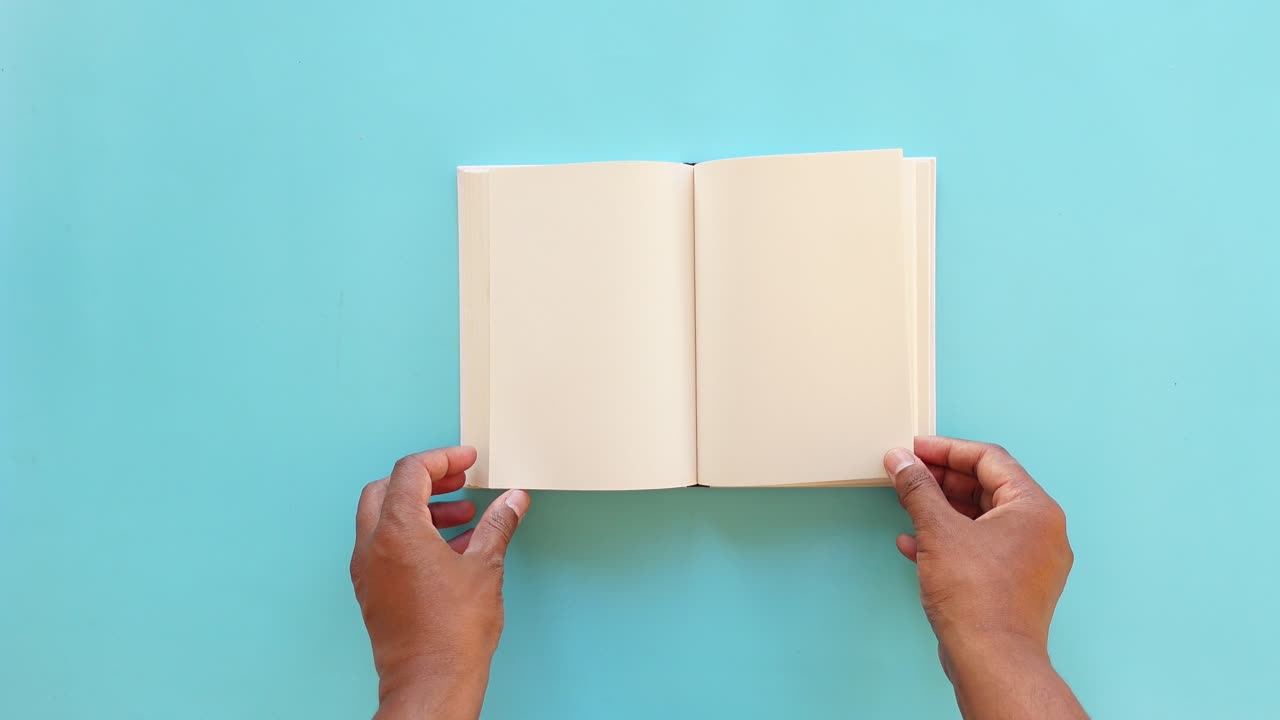 A person opens a white book with blank pages on a blue background