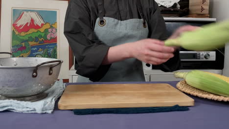 a-Japanese-female-chef-husking-corn-at-her-home-kitchen,-Tokyo,-Japan