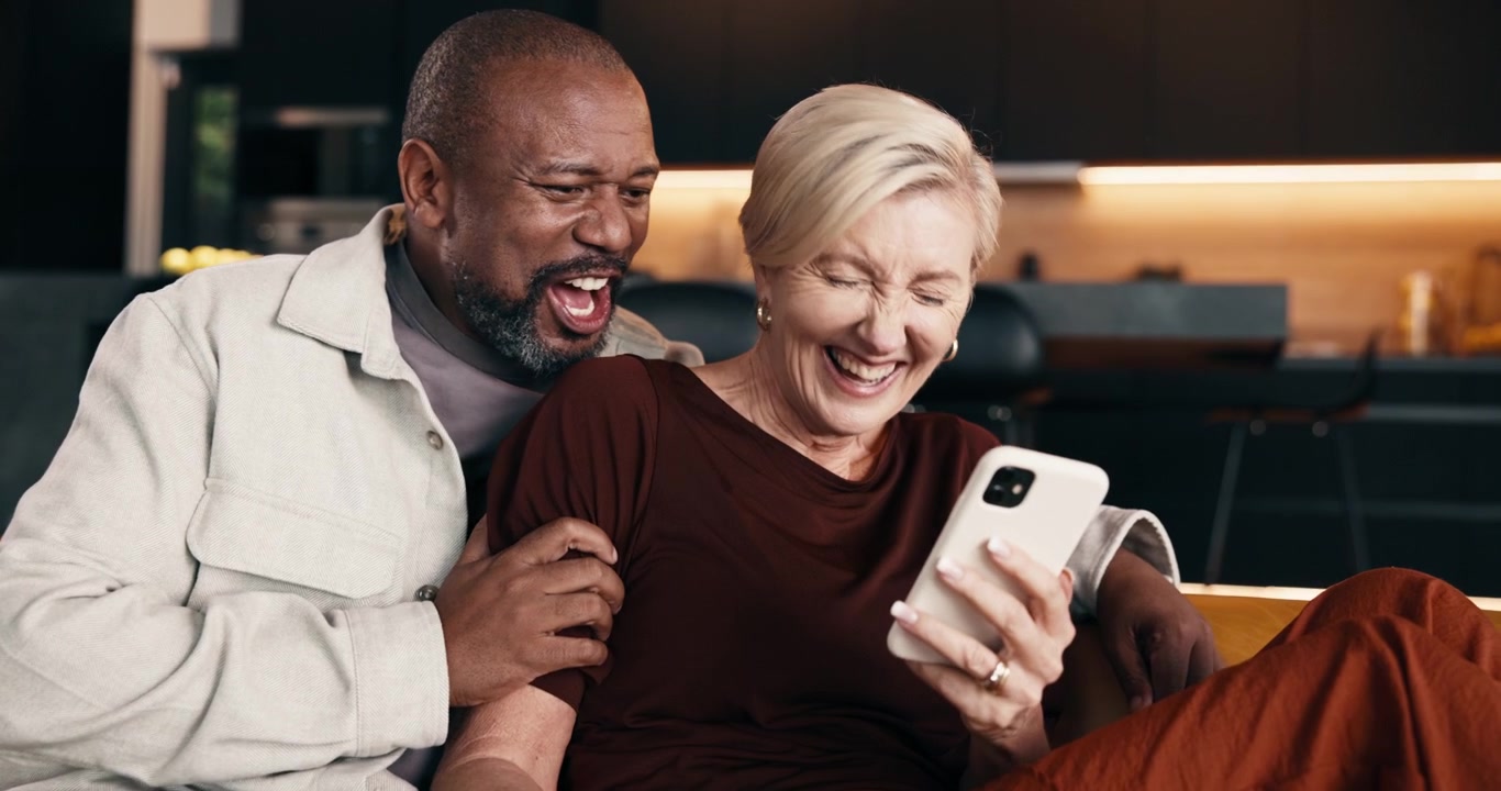 Happy Mature Couple Laughing While Looking at Smartphone Together