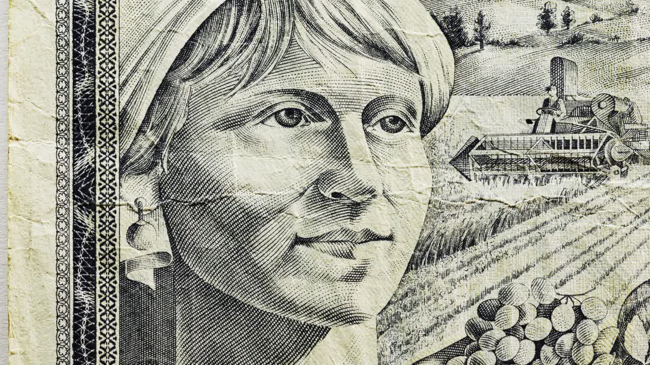 Close pan of Yugoslav 1000 dinara note showing female portrait and tractor in fields