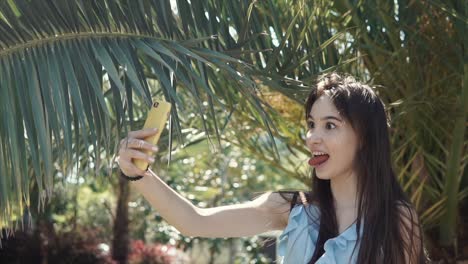 young woman taking a selfie under palm trees