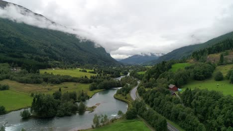 aerial forward dolly shot of car driving through the beautiful landscaping of the svortesvada fjord and river in stryn