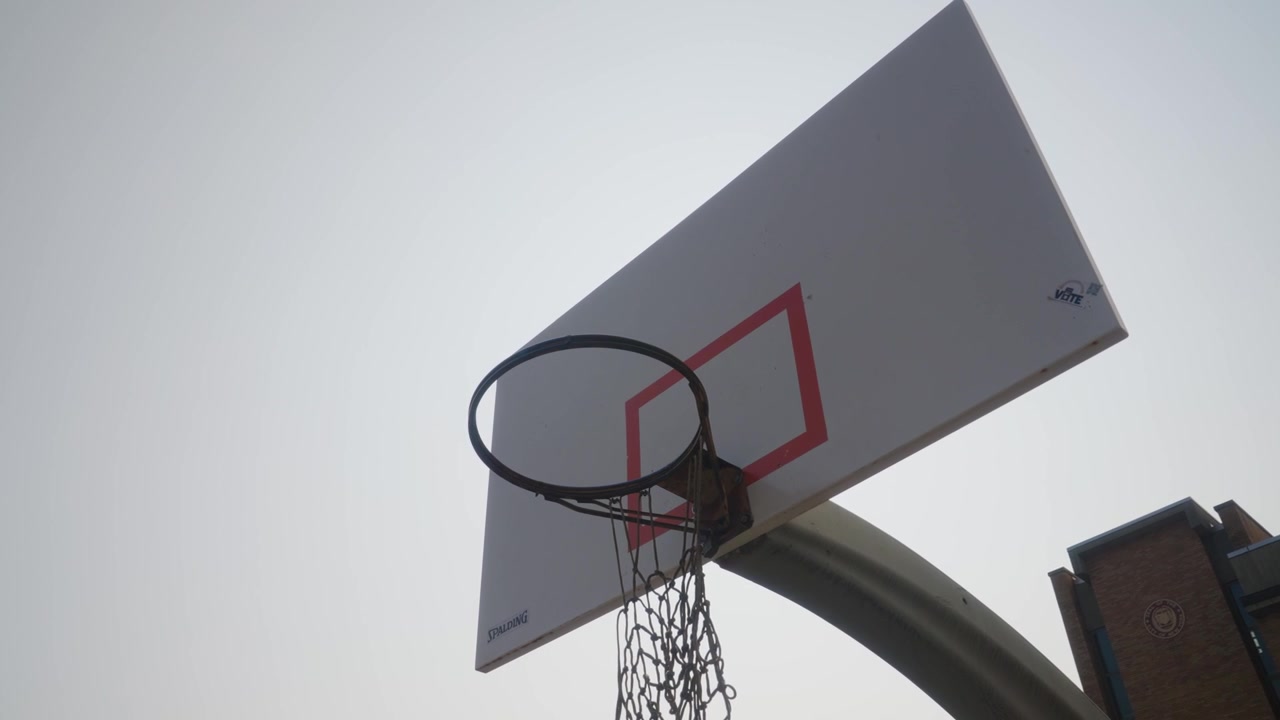 Canestro da basket esterno vuoto, anello e rete all'interno del cortile della scuola, New York, USA.
