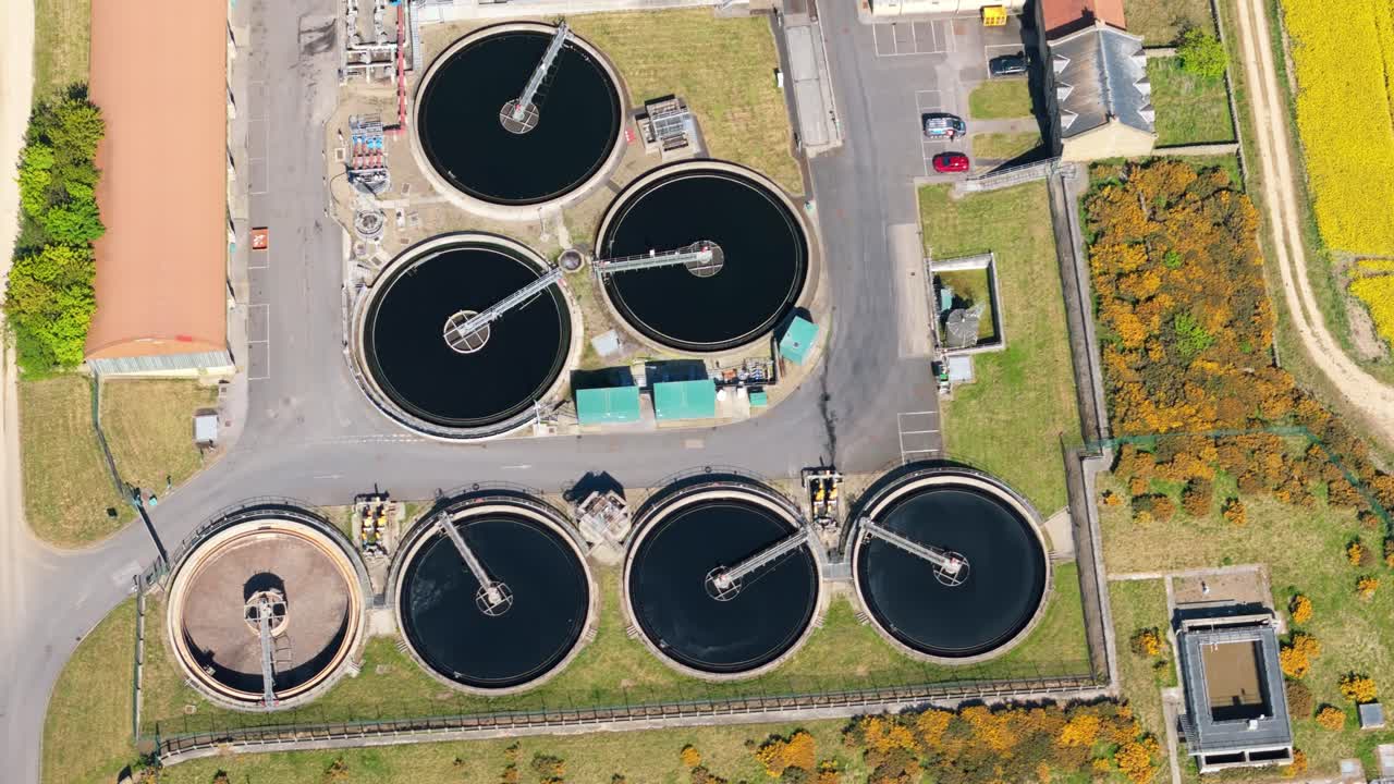 Aerial drone view of a wastewater treatment plant in a bright yellow rapeseed field on a sunny summer day in North Yorkshire, UK