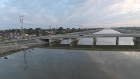 A-drone-glides-over-water-revealing-cars-driving-over-a-bridge
